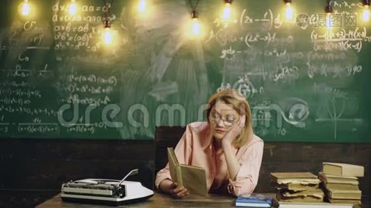 女人在学校教室里的绿色黑板背景上读一本书。 教室里的老师。 学习概念视频