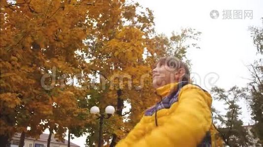快乐的女孩在秋天的公园里扔黄叶，微笑着。 慢动作。 秋天在公园休息的小女孩。视频