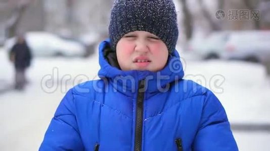 穿着蓝色羽绒服的少年扔雪。 冬天，降雪，特写视频