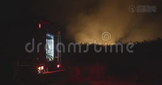 开着闪烁灯的消防车。 森林火灾时在野外焚烧草地背景下的消防车。 救援和救援视频