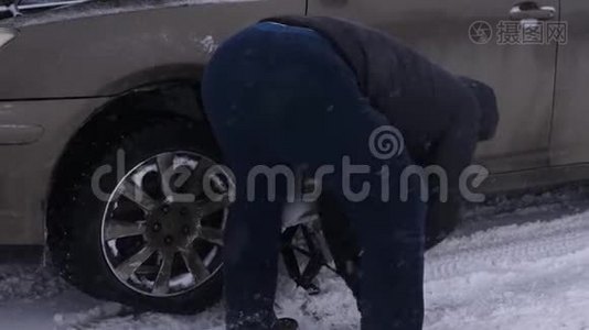 人在路上举起汽车千斤顶。 人类正在更换汽车车轮。 冬季在暴风雪中道路上更换车轮视频