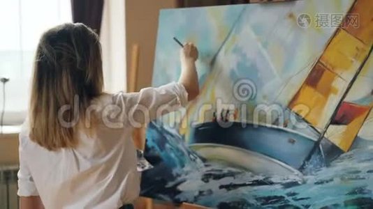 漂亮的女孩艺术家正忙于在画布上画海景，使用调色板、画笔和画架上的画布。视频