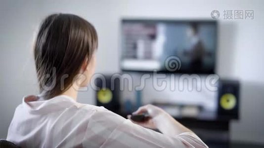 特写镜头从背后一个黑发女人看电视室内坐在沙发上。视频