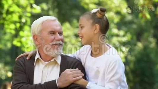 可爱的小女孩微笑着拥抱她的祖父，闲暇时间和家人在一起视频
