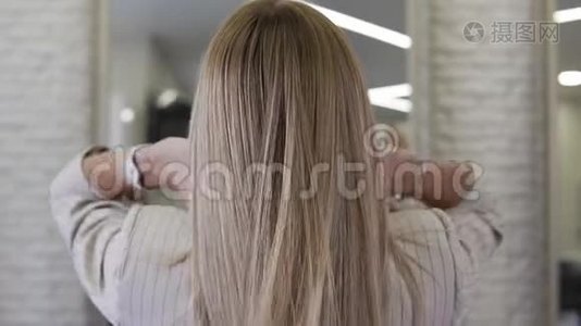漂亮的金发女人慢慢地把她长长的波浪状的头发扔到室内视频