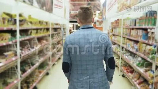 有手推车的人在超市里的货架上摆着货物，背面的风景，稳定的镜头。视频