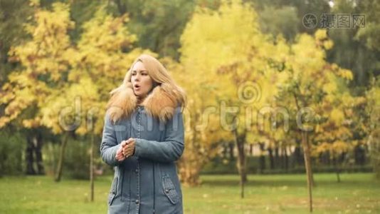 女士穿着时髦的外套在等男朋友的时候冻僵了，秋天的景象视频