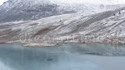 旅行者上升到一个高点。 他看着山峰和美丽的湖泊。 他拍摄了一幅美丽的风景视频