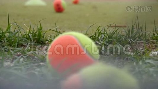 五颜六色的网球躺在网球场上的草地上，背景缓慢视频