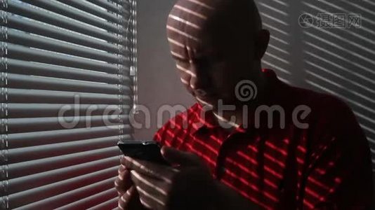 一名身穿红色t恤的男子在办公室里浏览手机信息视频