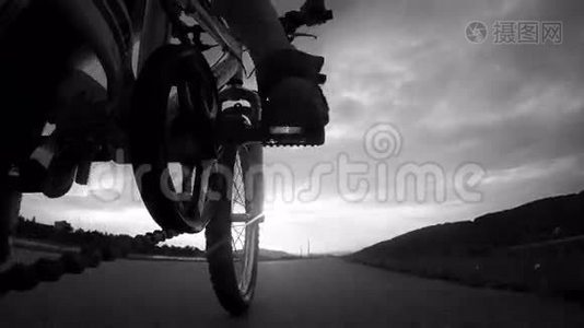 日落时分骑自行车的男孩的4k录像；从摄像机上看到的自行车车架视频