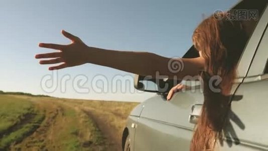 快乐的女性旅行者沿着乡间小路开车。 车窗上的手抓住了风。 长发女孩视频