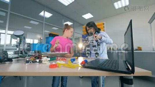 一个男孩修理机器人，而一个女孩在实验室里用平板电脑工作。 现代教育观念。视频