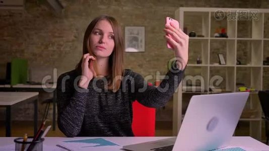 年轻的姜女在办公室背景上自拍和谈论smth。视频