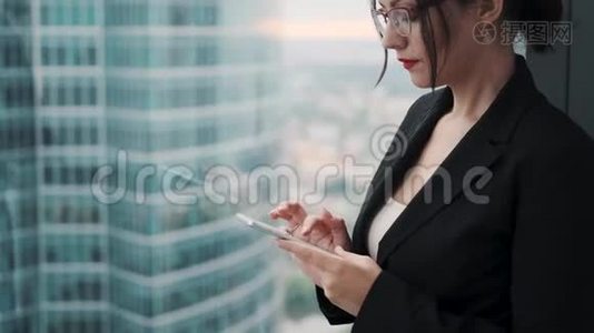穿商务服的年轻女性使用智能手机。 摩天大楼背景下的商业女性肖像。视频