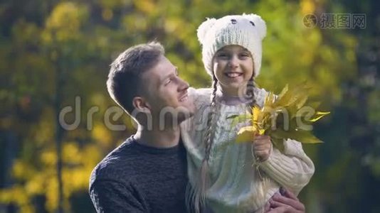 父亲抱着女儿戴着滑稽的帽子，一起度过空闲时间，秋天散步视频
