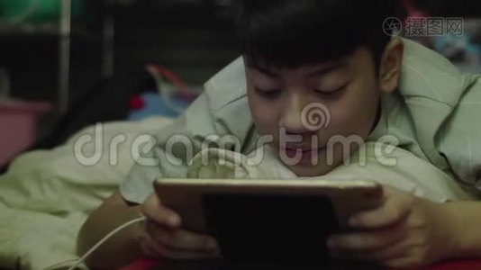 年轻的亚洲快乐男孩用笑脸在平板电脑上视频