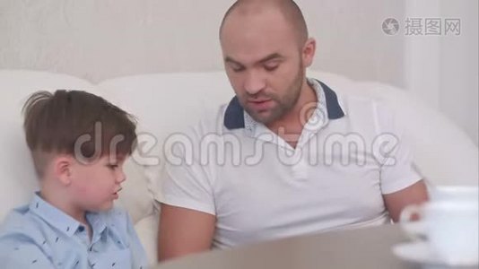 父子俩在家里的沙发上用数码平板电脑视频