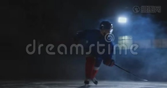 一个曲棍球运动员，手里拿着一根棍子，从黑暗中走出来，把冰球放在冰上视频