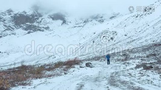 一个普通的中年男子在山区路线上旅行。 他一个人走在下雪的路上。视频