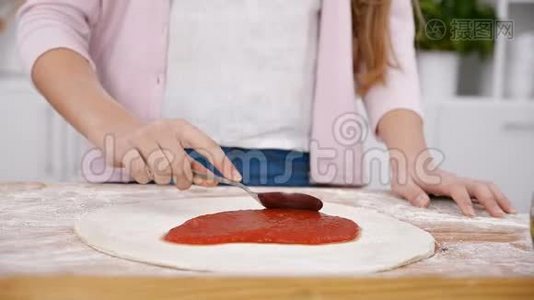 年轻女孩用手在面团上铺披萨酱视频