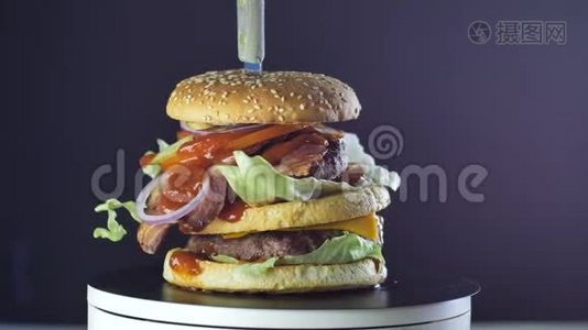 大的多汁汉堡，有两个切丝，西红柿，生菜和洋葱，倒入酱汁旋转，烤吧概念视频