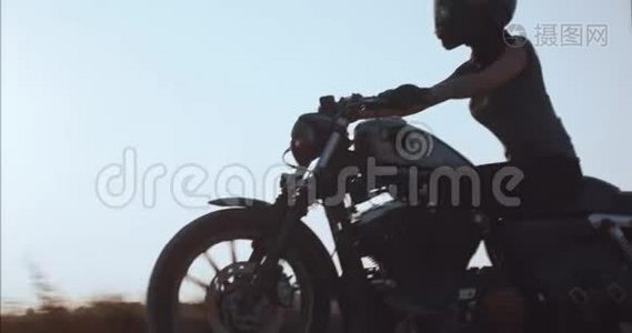 女孩驾驶摩托车在日落时沿着乡间小路行驶视频