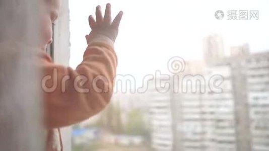 一个金发小男孩站在窗台上，望着窗外视频