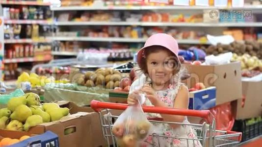 商店里的小女孩选择水果梨。 杂货店和购物车视频