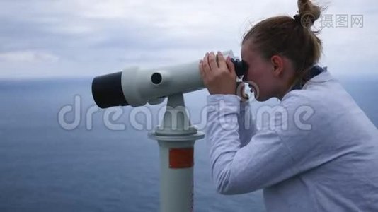 年轻女孩从陡峭的河岸透过望远镜看海洋视频
