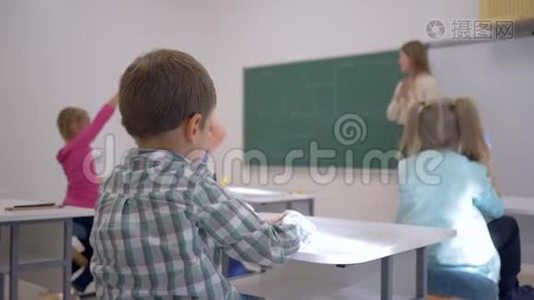孩子们的教育，孩子们在课堂上听老师在黑板上集中在学校的课堂上视频
