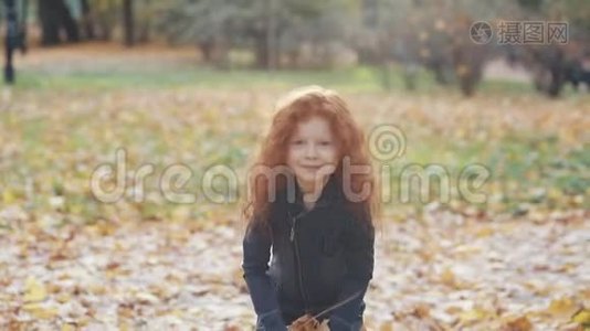 特写可爱的小女孩在缓慢的动作中投掷黄色的秋叶。 那孩子正站在公园里视频