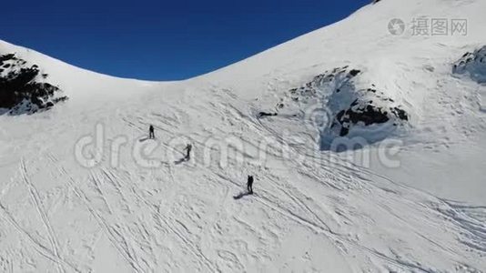 空中/无人驾驶飞机射击高山和滑雪者在山上行走，并提供滑雪`和支撑杆视频