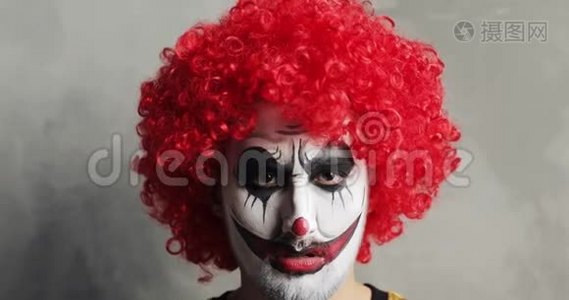 恐怖的愤怒男人小丑的肖像，万圣节化妆和红色卷曲假发。视频