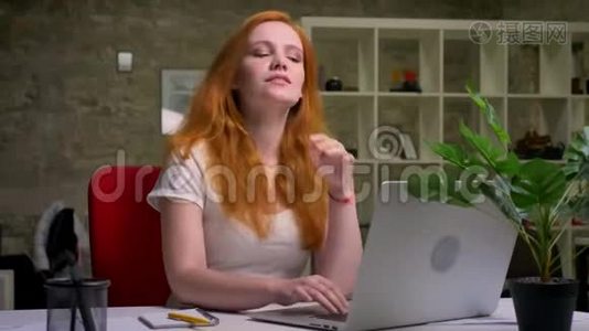 佩蒂微笑着的白种人生姜女商人正在愉快地看着笔记本电脑屏幕，手牵着她的头视频