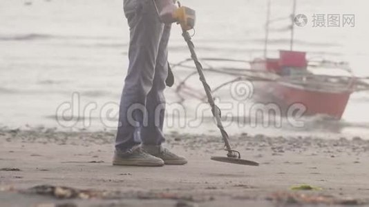 人类正在海滩上用金属探测器探测日出时在沙滩上寻找宝藏，双腿特写视频