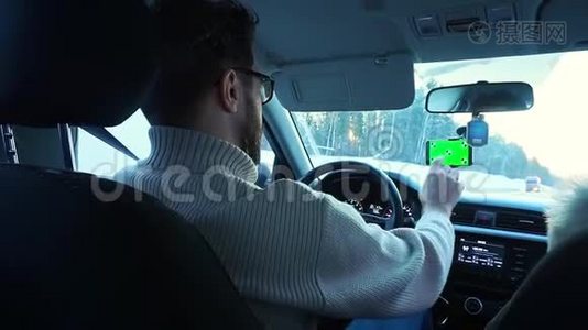 冬天开车的人。 智能手机有一个绿色的屏幕贴在挡风玻璃上，它把手指按在挡风玻璃上视频