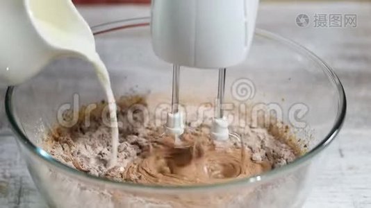 人手将牛奶和面粉加入碗中的糖混合蛋中，制成甜面糊作为蛋糕。视频