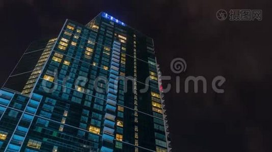 夜空，云层高于现代摩天大楼，明亮的窗户建筑时间推移。视频