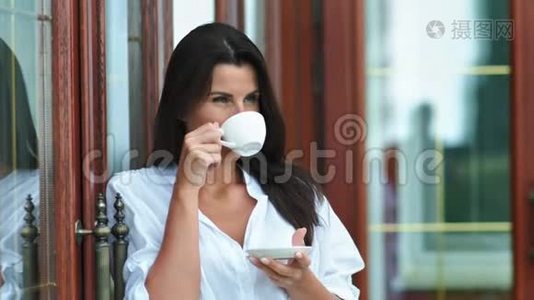 美丽的微笑女人在户外休息时，手拿着热咖啡或茶，手拿着杯子和茶碟视频