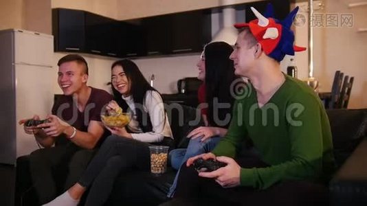两个年轻人在玩游戏，而他们的女朋友在谈论游戏视频
