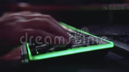一个男人正在一个绿色背光的键盘上打字。好计划。美丽的灯光。黑客。视频