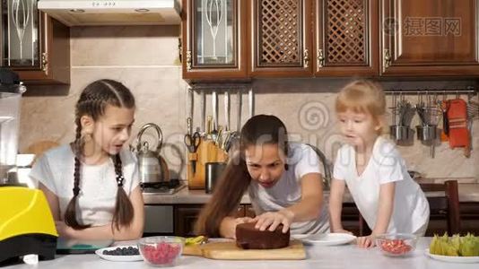 幸福的家庭妈妈和女儿们正在一起做生日蛋糕。视频