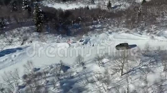 一辆黑色面包车在积雪覆盖的道路上行驶的华丽空中镜头视频