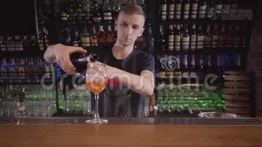 年轻的酒保专注于把一杯清爽的威士忌或酒精鸡尾酒倒入一杯充满冰的杯子里。视频