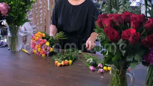 花商妇女作品制作花束由五颜六色的玫瑰在商店，手特写。视频