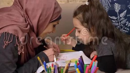 穆斯林母女俩躺在沙发上，用彩色铅笔作画，幸福的家庭观念，家里的舒适视频