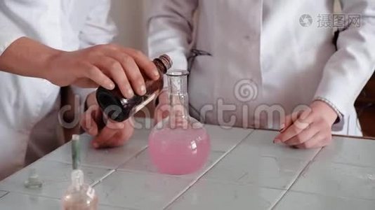 化学实验。 实验室工作人员将化学液体倒入带有粉红色溶液的烧瓶中。视频