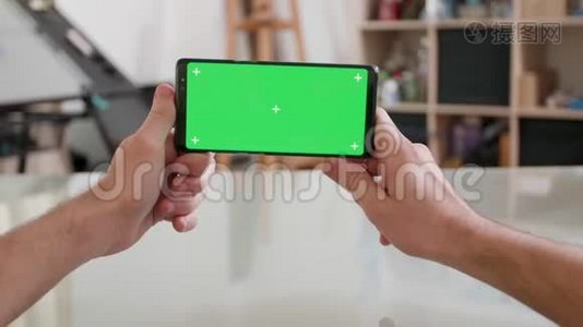 男人的视角：水平手持一部绿色屏幕的智能手机视频