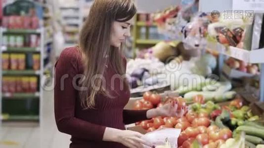 小女孩在超市的杂货店买蔬菜，然后放进塑料袋里视频